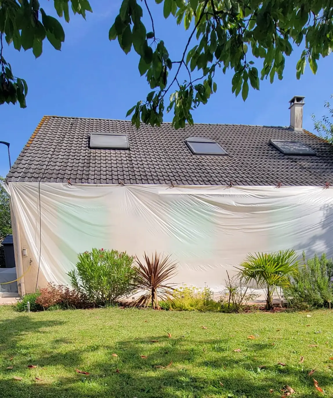 Pavillon en chantier, façade protégée par une bâche pendant les travaux